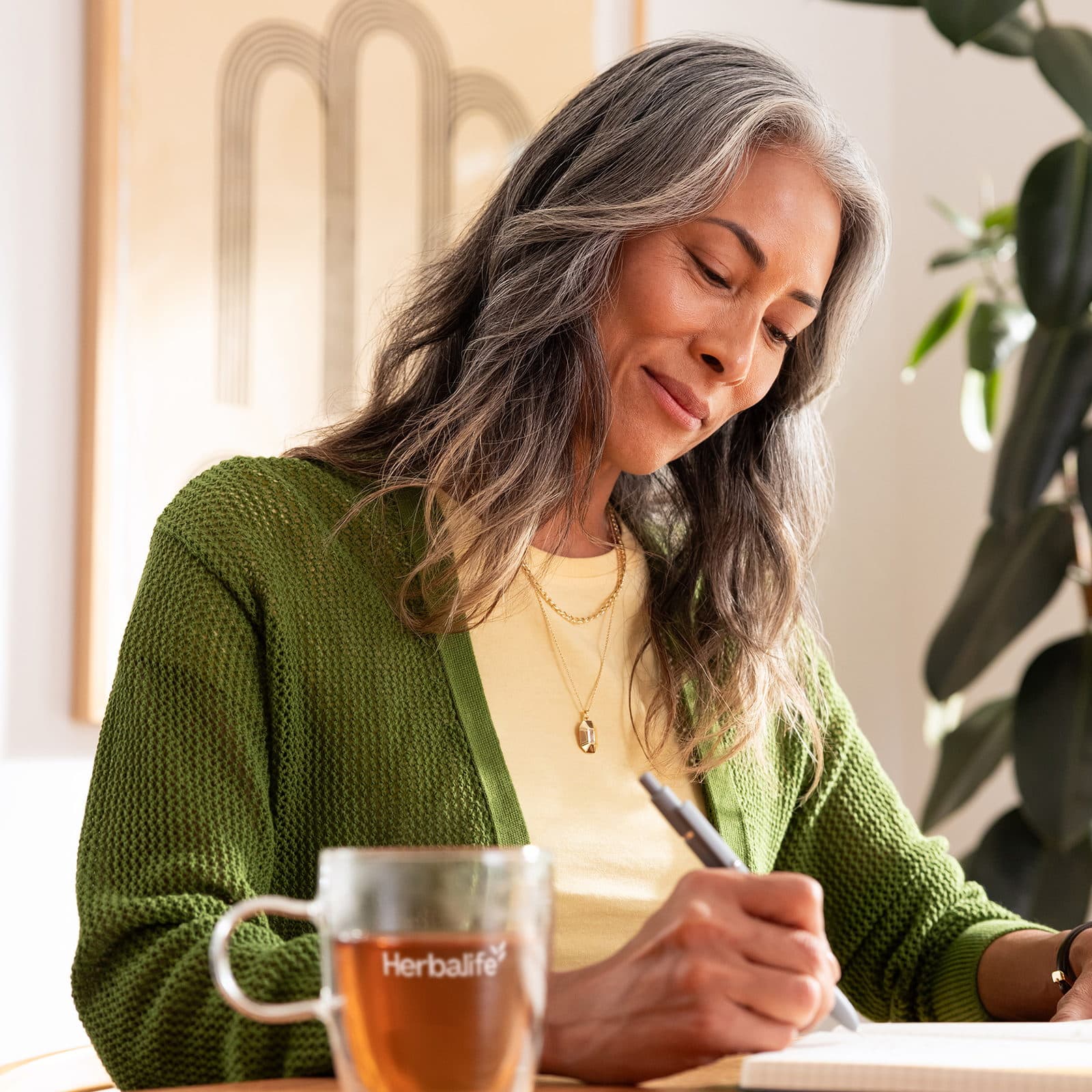 Woman writing in notepad with a cup of tea