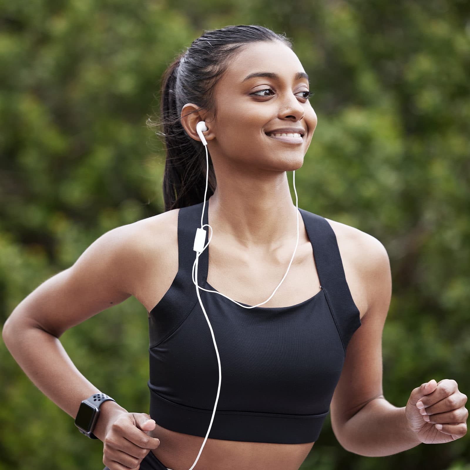Smiling woman with headphones in on run in the park