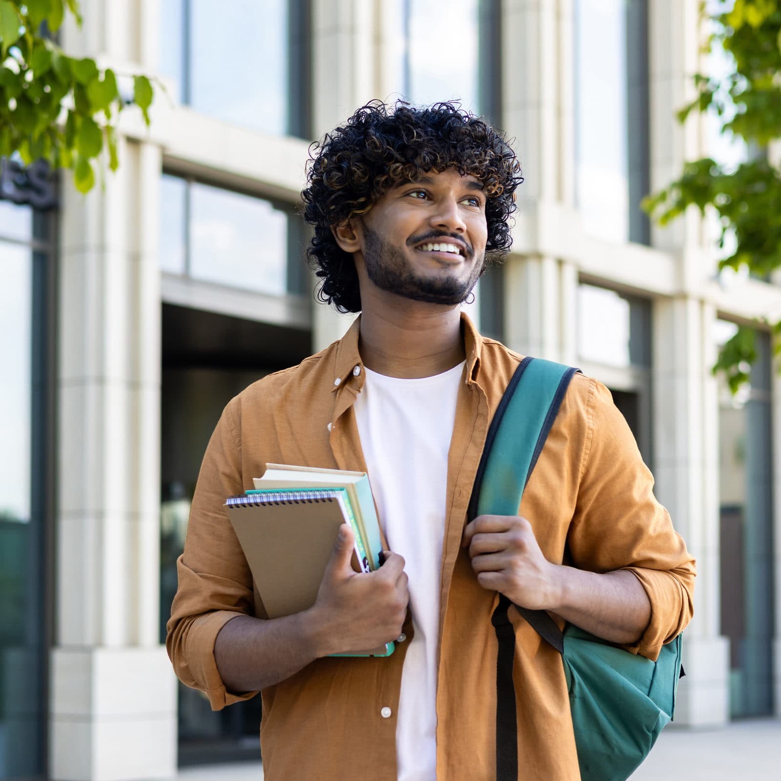 Man holding books walking outdoors