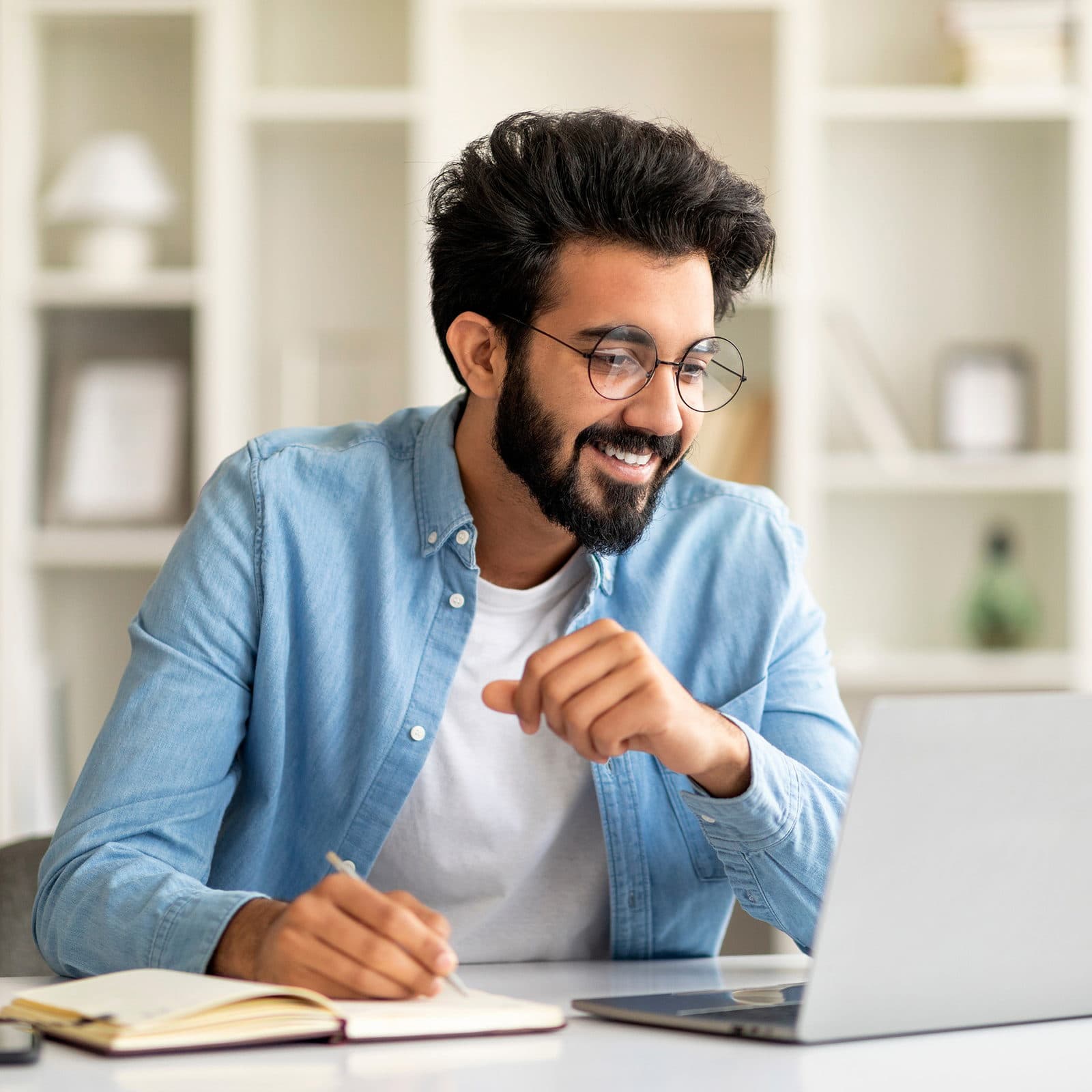 Man working on laptop and taking notes