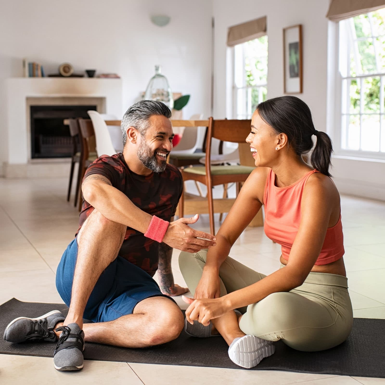 A couple taking a break sat on yoga mat smiling
